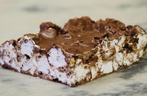 A close-up of a chocolate marshmallow treat, featuring a layered texture with chunks of chocolate and marshmallows.