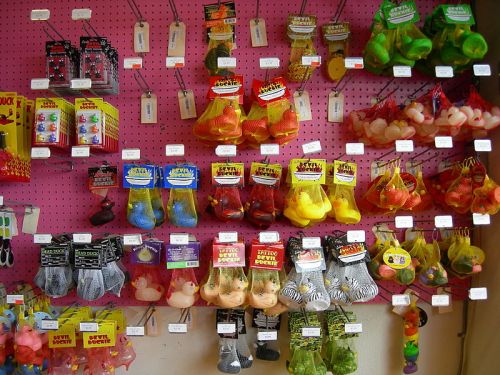 A colorful display of various rubber ducks and novelty toys hanging on a pink wall.