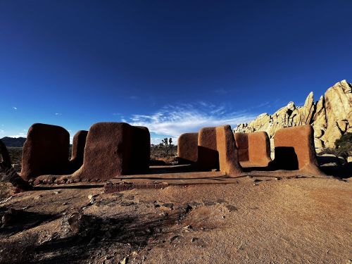 A desert landscape featuring large, weathered rock formations and a clear blue sky.