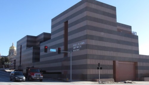 Modern building with horizontal stripes, labeled "State of Iowa Historical Building," near traffic lights and a dome structure.