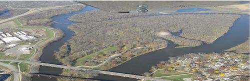 Aerial view of a winding river surrounded by trees and a small town with colorful houses along the banks.