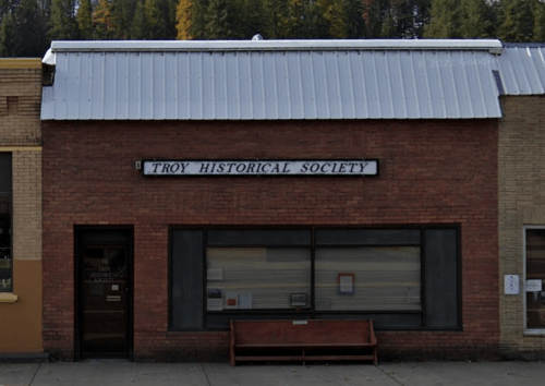 Front view of the Troy Historical Society building, featuring a brick facade and a bench outside.
