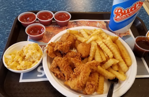A plate of fried chicken, crinkle-cut fries, macaroni and cheese, and dipping sauces on a tray.
