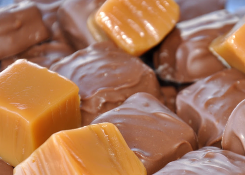 Close-up of assorted chocolate-covered caramel candies, featuring smooth, shiny surfaces and rich caramel centers.