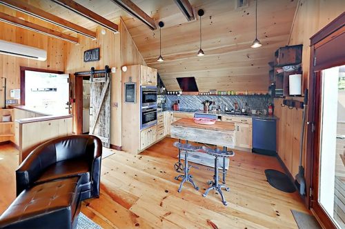 Cozy wooden kitchen with modern appliances, a central island, and a rustic design featuring exposed beams and warm tones.