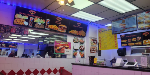 Interior of a fast-food restaurant with menu boards, bright lights, and a counter displaying food options.