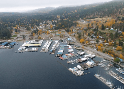 Aerial view of a marina with boats, surrounded by autumn-colored trees and a small town in the background.