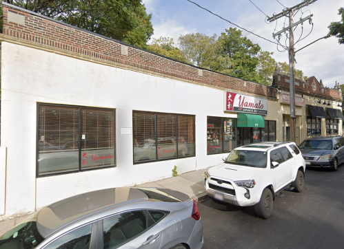 Exterior view of Yamato Japanese Restaurant, featuring large windows and parked cars on a tree-lined street.