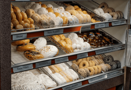 A display case filled with various types of donuts and pastries, including glazed, powdered, and filled options.