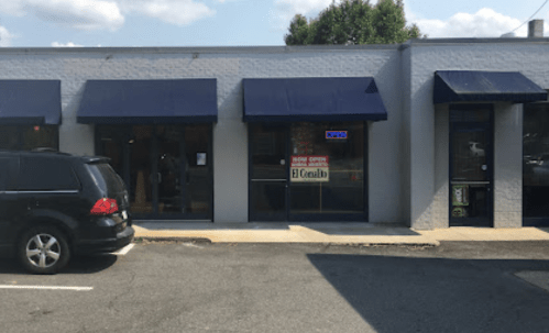 A storefront with blue awnings, a "For Rent" sign, and a parked black SUV in front.