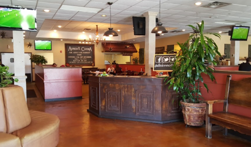 Interior of a restaurant featuring wooden decor, seating areas, and TVs showing a sports game.