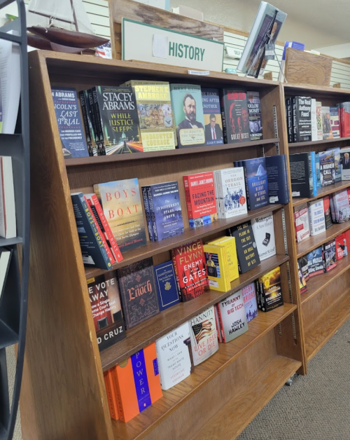 A wooden bookshelf displaying various history books, with a sign labeled "HISTORY" at the top.