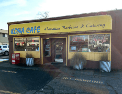 Exterior of Kona Cafe, featuring a bright yellow sign, open door, and no parking sign in front.