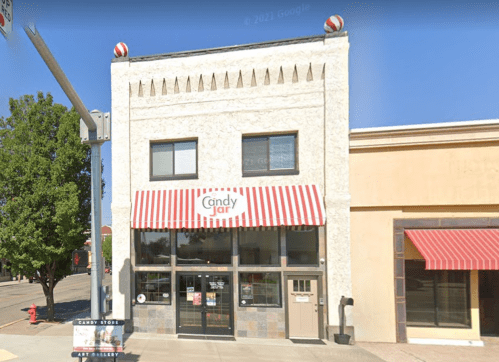 A storefront of a candy shop called "Candy Jar" with red and white striped awning and decorative elements on the facade.