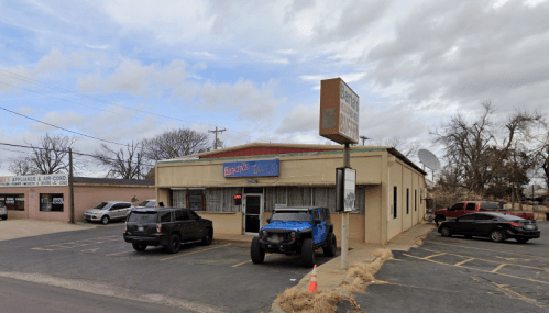 A small restaurant building with a sign reading "Berta's Tacos," surrounded by parked cars and a cloudy sky.