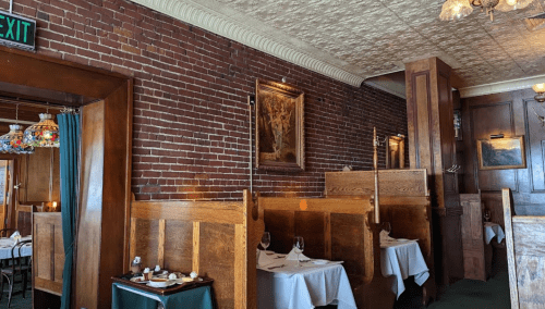 Cozy restaurant interior featuring brick walls, wooden booths, and elegant table settings with candles.