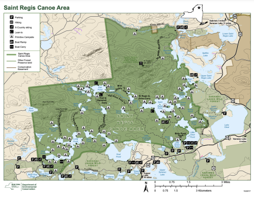 Map of the Saint Regis Canoe Area, showing trails, parking, campsites, and water bodies in a green and beige layout.