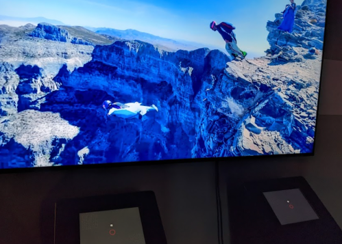 A breathtaking view of a canyon with a person base jumping off a cliff, captured on a large screen.