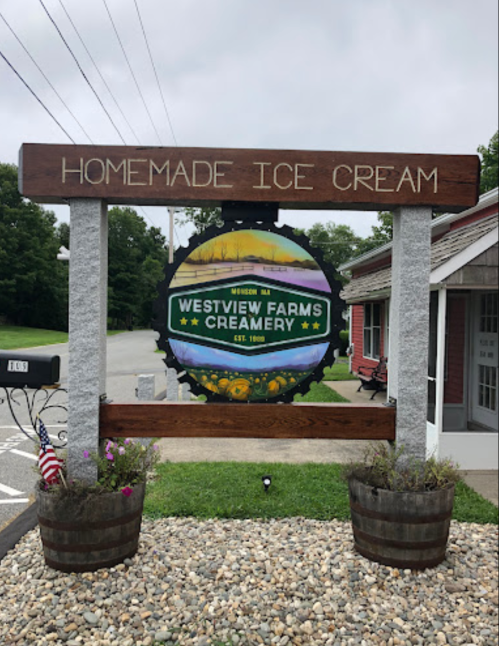 Sign for Westview Farms Creamery featuring "Homemade Ice Cream" and a colorful logo, surrounded by flower pots.