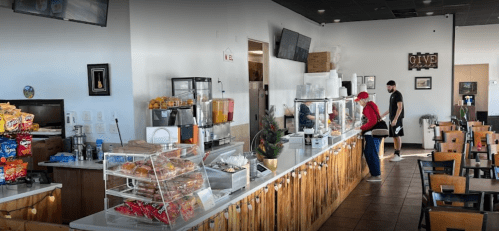 A bright café interior with a counter displaying snacks and drinks, and customers interacting at the service area.