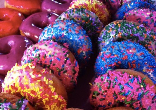 A colorful assortment of donuts with vibrant icing and sprinkles in various shades of pink, blue, and yellow.