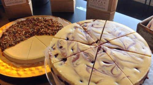 Two types of cheesecake on display: one with a swirl design and the other topped with nuts, both sliced for serving.