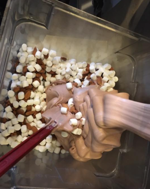 A mixing bowl filled with chocolate batter, mini marshmallows, and chopped almonds.