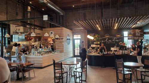 A modern coffee shop interior with a counter, seating area, and staff preparing drinks. Bright and inviting atmosphere.