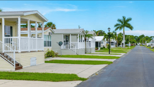 A quiet street lined with pastel-colored houses and palm trees under a clear blue sky.