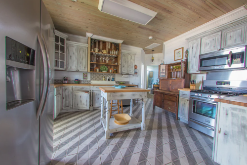 Bright kitchen with wooden cabinets, an island, and modern appliances, featuring a cozy, rustic design.