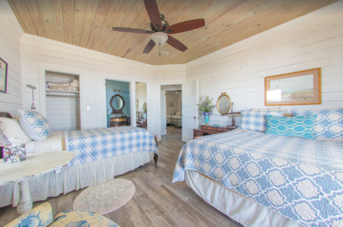 Bright, airy bedroom with two beds, wooden ceiling, and light decor, featuring a cozy, inviting atmosphere.