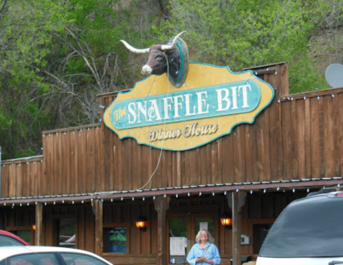 A wooden restaurant exterior with a sign reading "The Snaffle Bit Dinner House" and a bull's head mounted above.