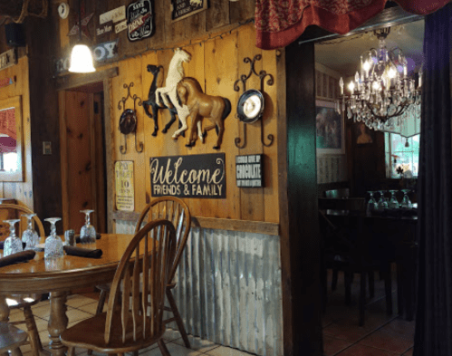 Cozy restaurant interior with wooden decor, horse wall art, and a chandelier, inviting friends and family.