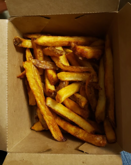 A takeout box filled with golden-brown French fries.