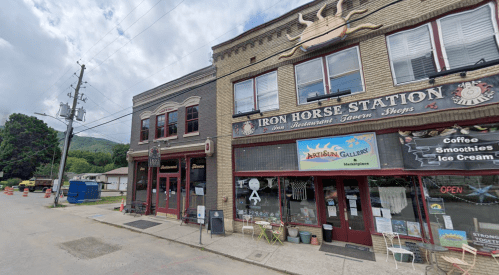 A street view of Iron Horse Station, featuring shops and a restaurant, with cloudy skies overhead.