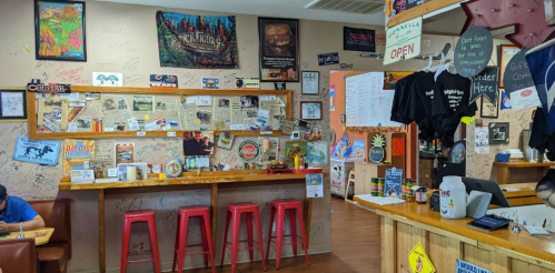 A cozy restaurant interior with wooden counters, red stools, and walls covered in posters and signatures.