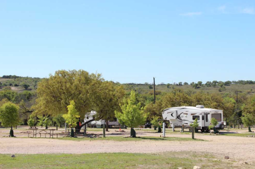 A scenic campsite with RVs, green trees, and a clear blue sky in a rural area.