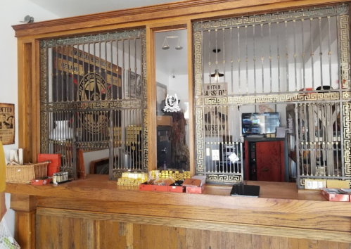 A vintage wooden counter with ornate metalwork and glass partitions, featuring scales and various items displayed.