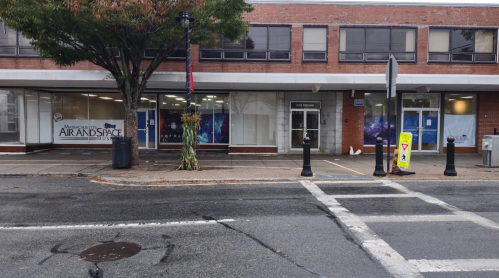 A street view of the Massachusetts Air and Space Museum building with trees and a crosswalk in the foreground.