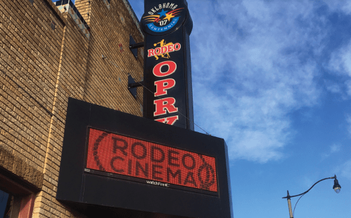 Sign for Rodeo Cinema with a blue sky in the background, featuring the Oklahoma flag and "Rodeo Opry" text.