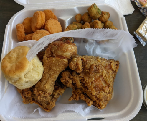A takeout container with fried chicken, a biscuit, okra, and chicken nuggets.