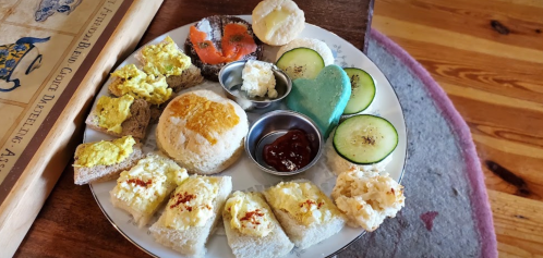 A plate of assorted snacks including bread, cucumber slices, cream cheese, and a variety of spreads and toppings.