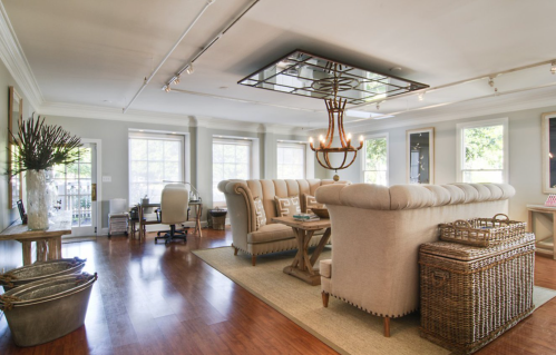 A spacious, modern living room with a large sofa, wooden floors, and stylish decor, featuring natural light from windows.