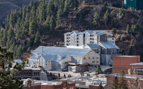 A multi-story building nestled among trees on a hillside, with a mix of modern and traditional architecture.