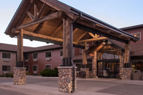 A rustic hotel entrance featuring wooden beams and stone accents, with a welcoming atmosphere at dusk.