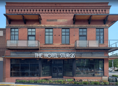 Exterior view of The Hotel Sturgis, featuring a brick facade, large windows, and a welcoming entrance.