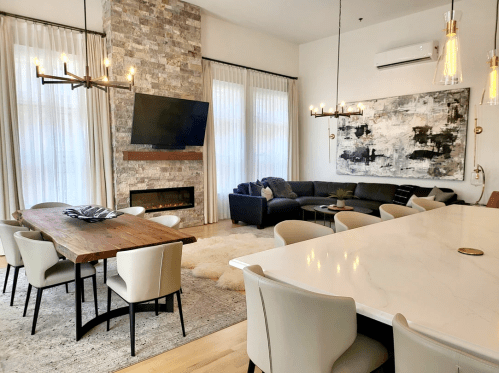 Modern living space featuring a stone fireplace, large TV, dining table, and cozy seating area with artwork.