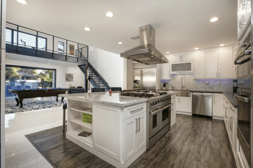 Modern kitchen with stainless steel appliances, white cabinets, and an open layout leading to a stylish living area.