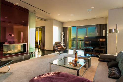 Modern living room with large windows, a sleek fireplace, and stylish furniture, featuring a view of the outdoors.