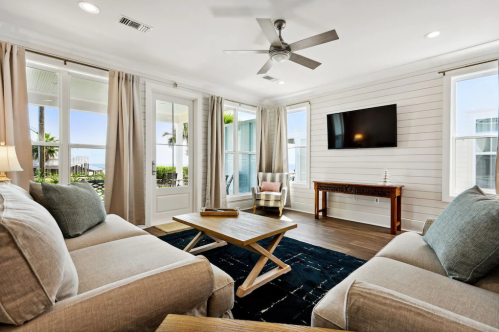 Bright living room with large windows, a ceiling fan, and a cozy seating area overlooking a scenic view.